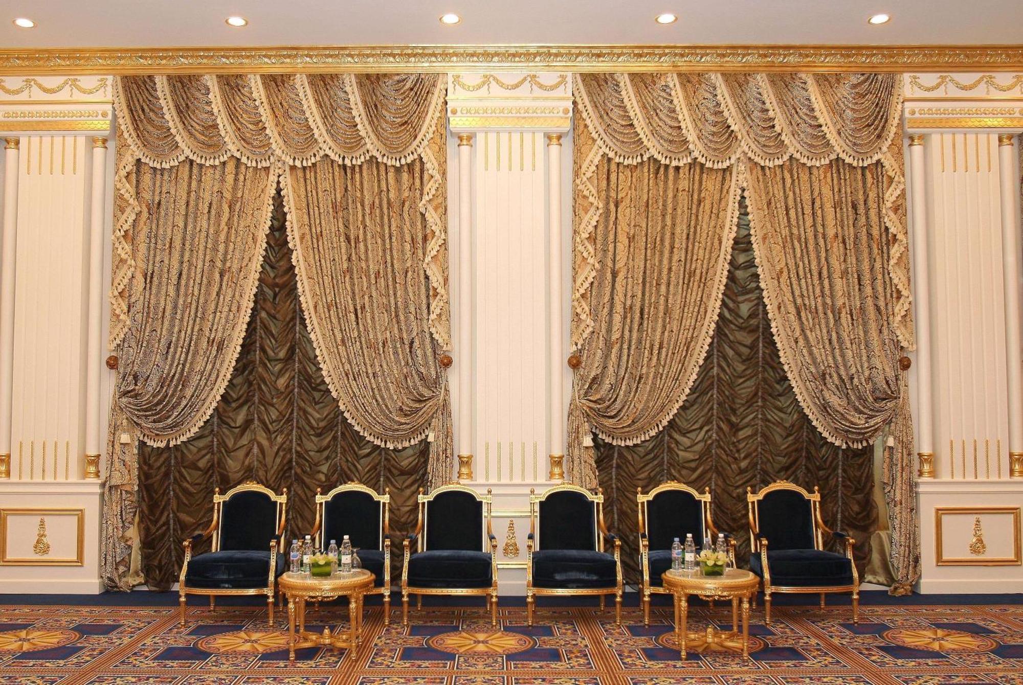 Grand Regency Doha, Trademark Collection By Wyndham Exterior foto The photo shows an elegantly decorated interior space. There are two sets of opulent curtains on the walls, featuring rich fabrics with ornate designs and gold accents. The curtains are paired with decorative tiebacks. In front of the curtains, there