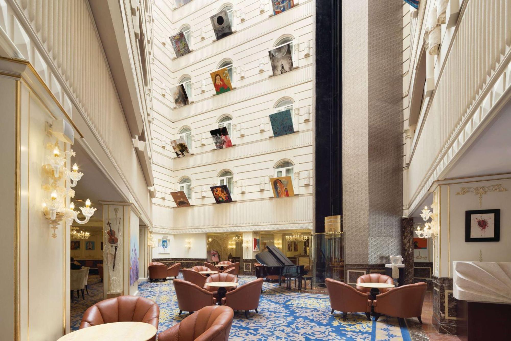 Grand Regency Doha, Trademark Collection By Wyndham Exterior foto The photo depicts the interior of a spacious, upscale hotel lobby. The design features high ceilings and multiple levels, with large windows that create a bright and airy atmosphere. Elegant light fixtures adorn the walls, and the floor is covered wi