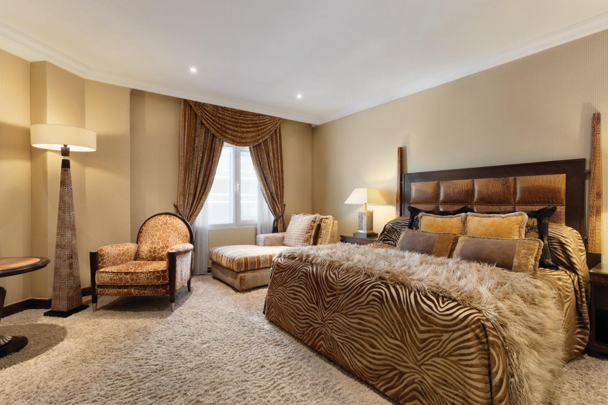Grand Regency Doha, Trademark Collection By Wyndham Exterior foto The photo shows a stylishly decorated bedroom. The focal point is a large bed dressed in fabrics with a rich, textured appearance, possibly featuring a zebra print or similar design. On either side of the bed, there are small bedside lamps. 

Adjacen